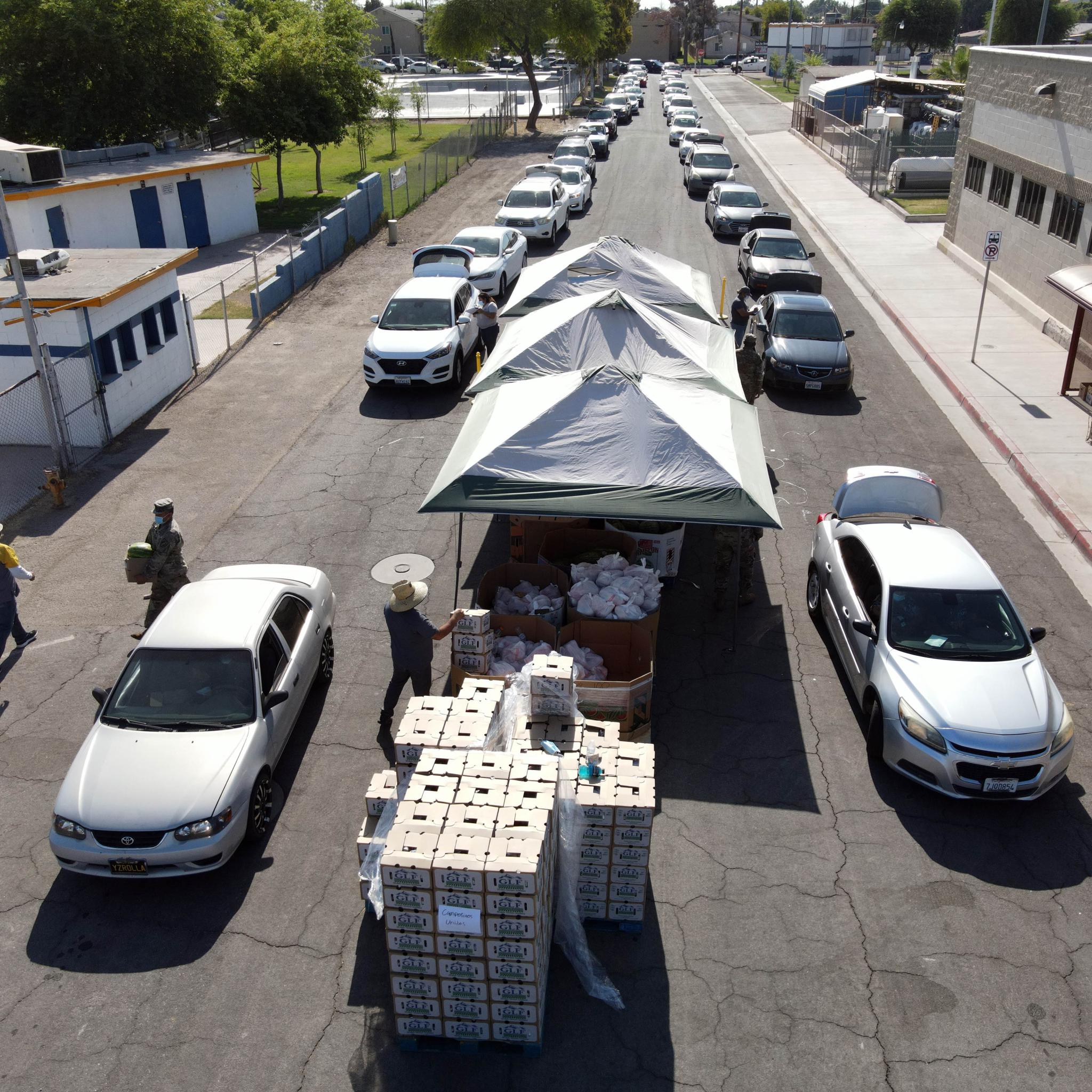 Cars lined up down a street for a drive through food distribution