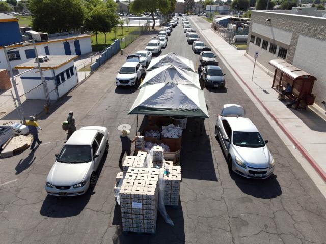 Cars lined up down a street for a drive through food distribution